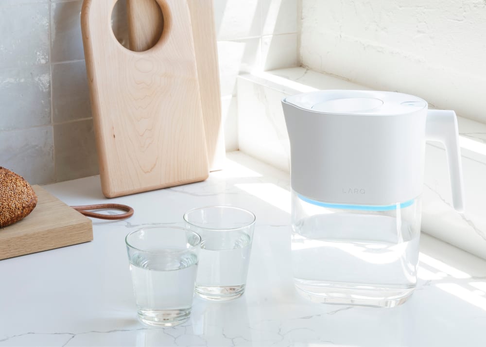 Larq pitcher on the table with purified water and 2 glasses of purified water